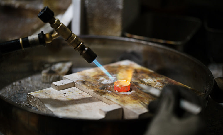 Jeweler soldering with a torch—annealing silver ring during hand fabrication.
