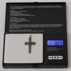 Crucifix pendant without its chain on a digital pocket scale whose display reads 3.65 g
