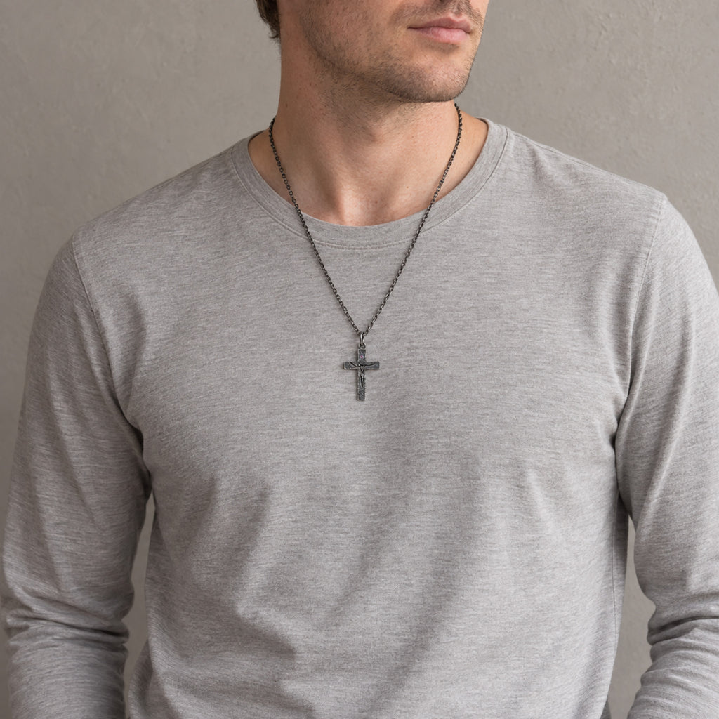 Man in a gray long-sleeve T-shirt wearing the oxidized crucifix on a dark chain at mid-chest