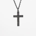 Oxidized sterling silver crucifix pendant with a small purple cubic zirconia above the carved figure of Jesus, on a dark chain against a light gray background