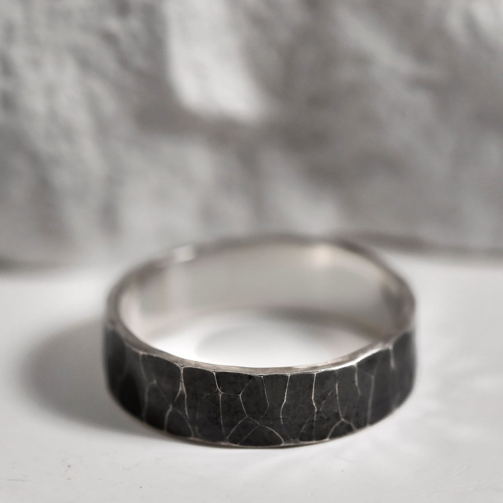 Close-up of the dark hammered surface on a rustic sterling silver wedding or promise band.