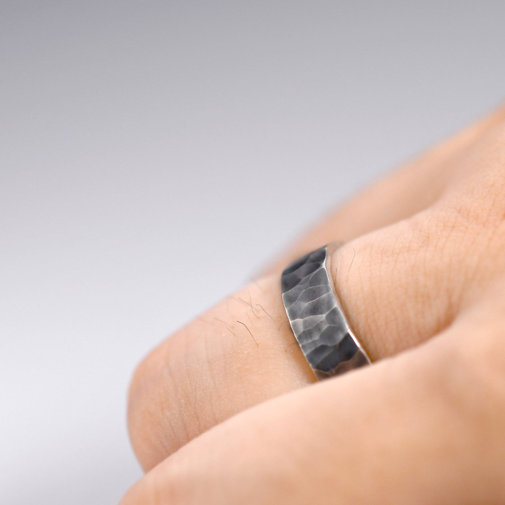 Handmade hammered sterling silver ring shown on hand, designed as a bold everyday band.