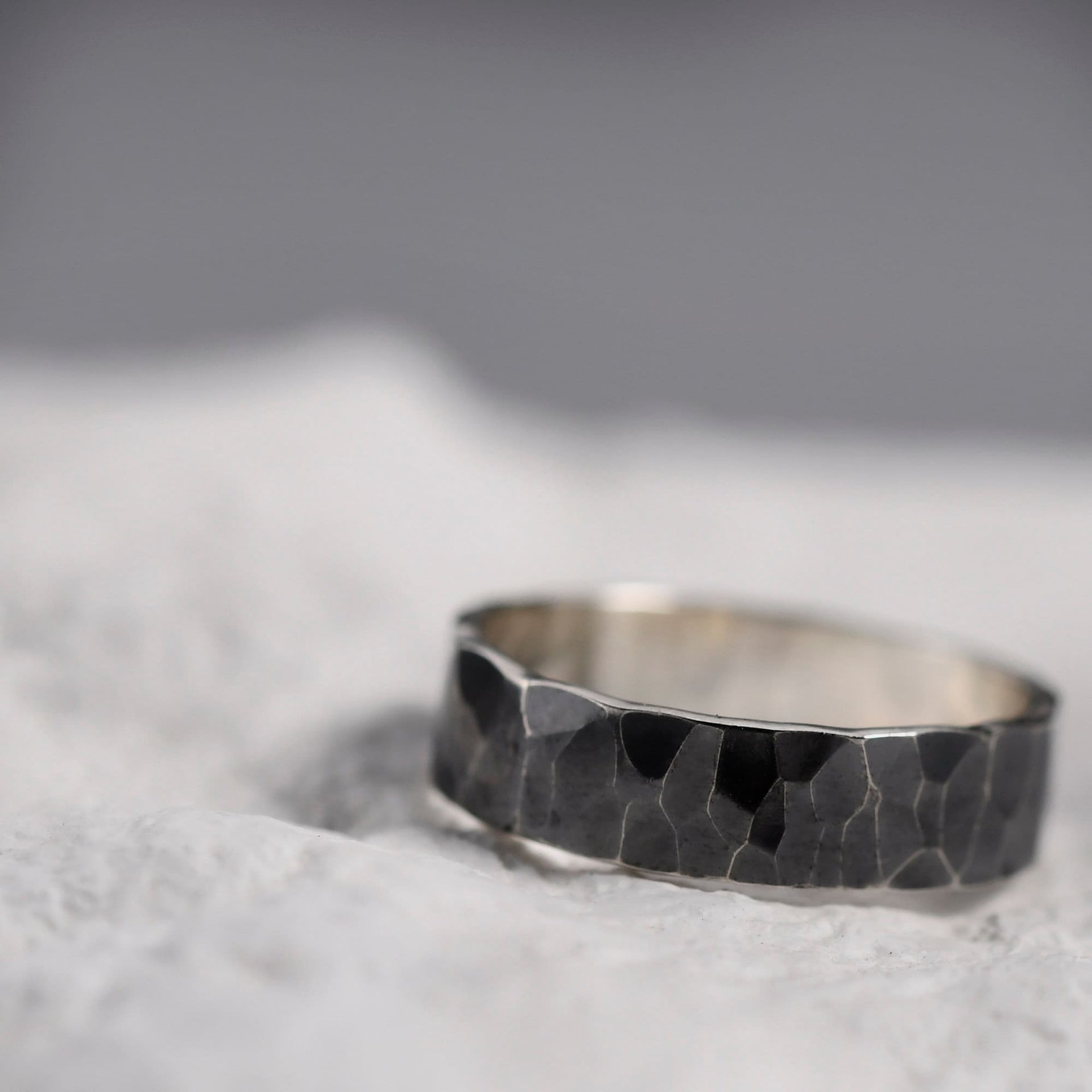 Side view of the oxidized silver ring with deep hammered texture and polished edge contrast.