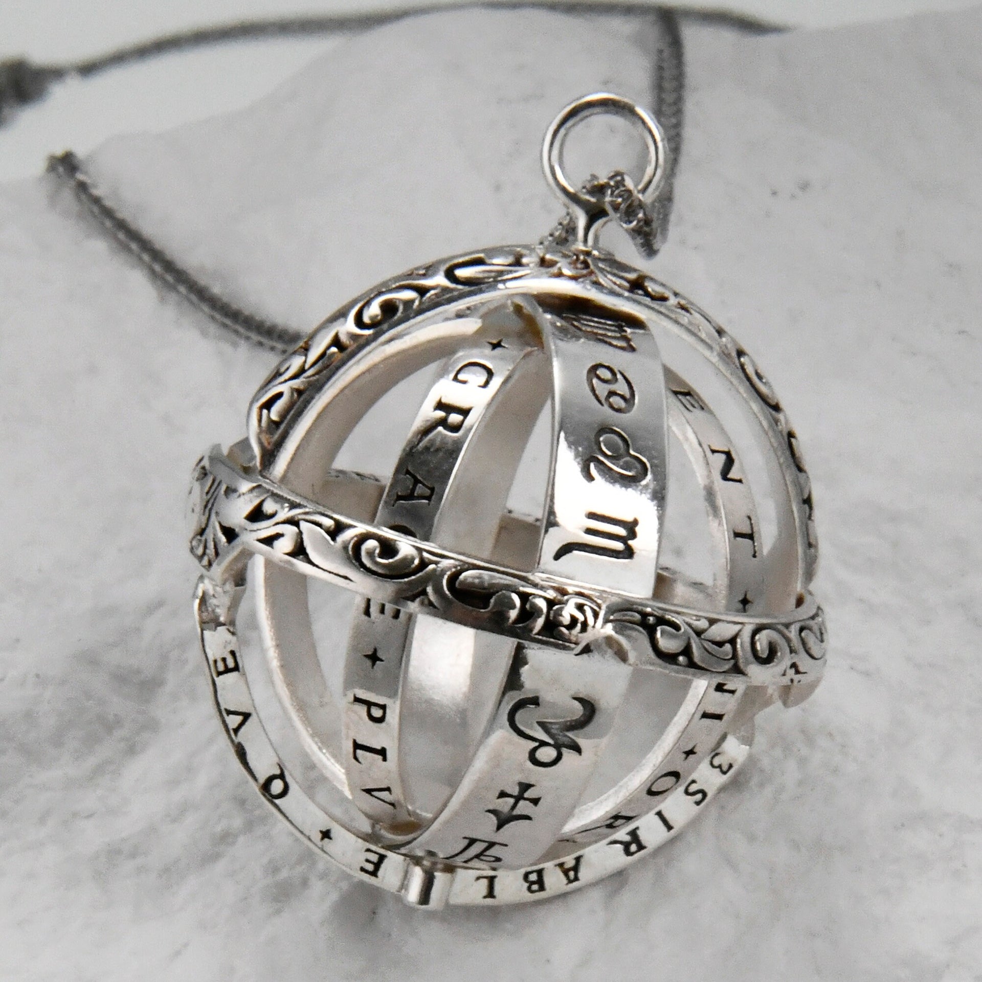 Birthstone armillary sphere pendant opened to show layered celestial rings