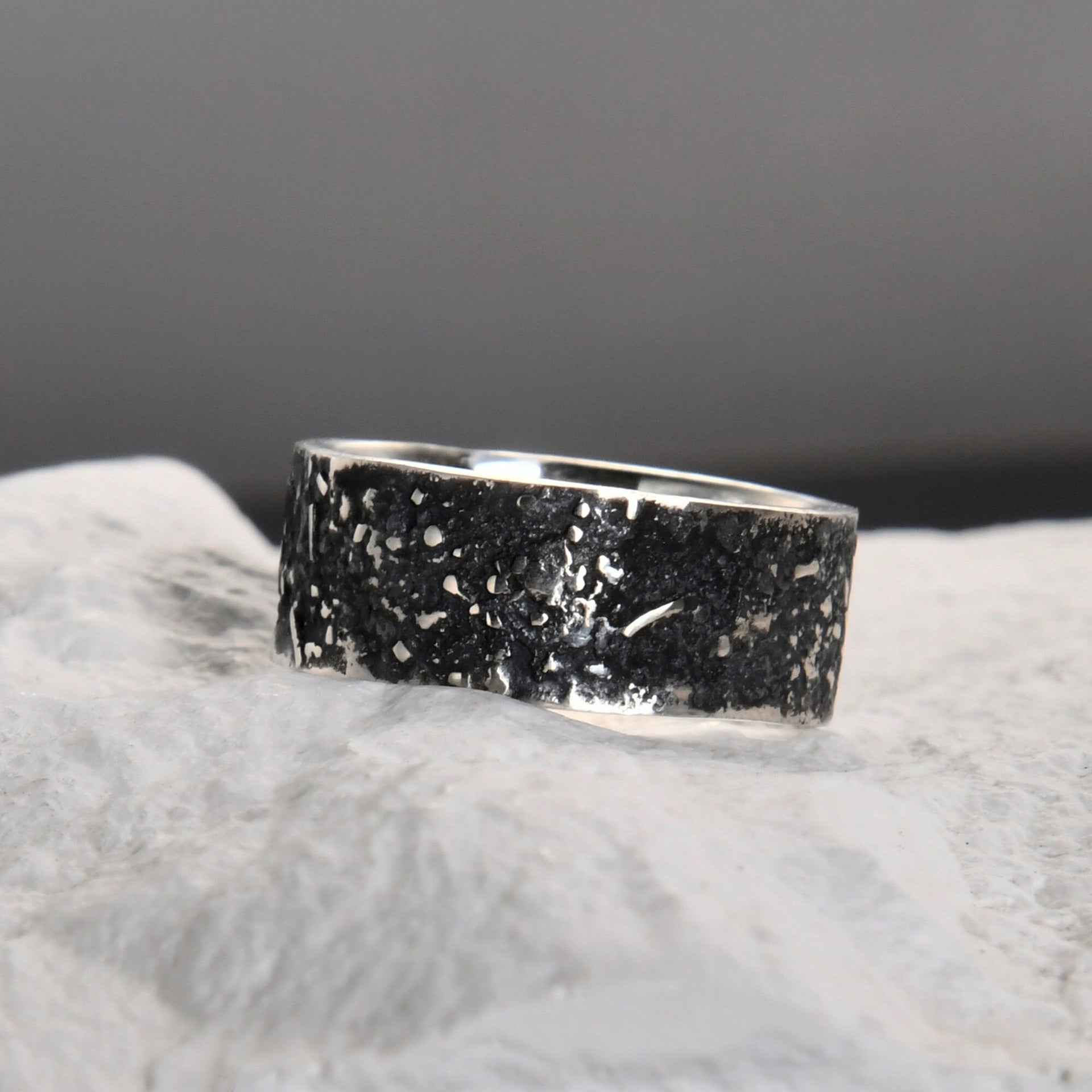 Close-up of the dark fused lava and galaxy texture on a rustic sterling silver band.