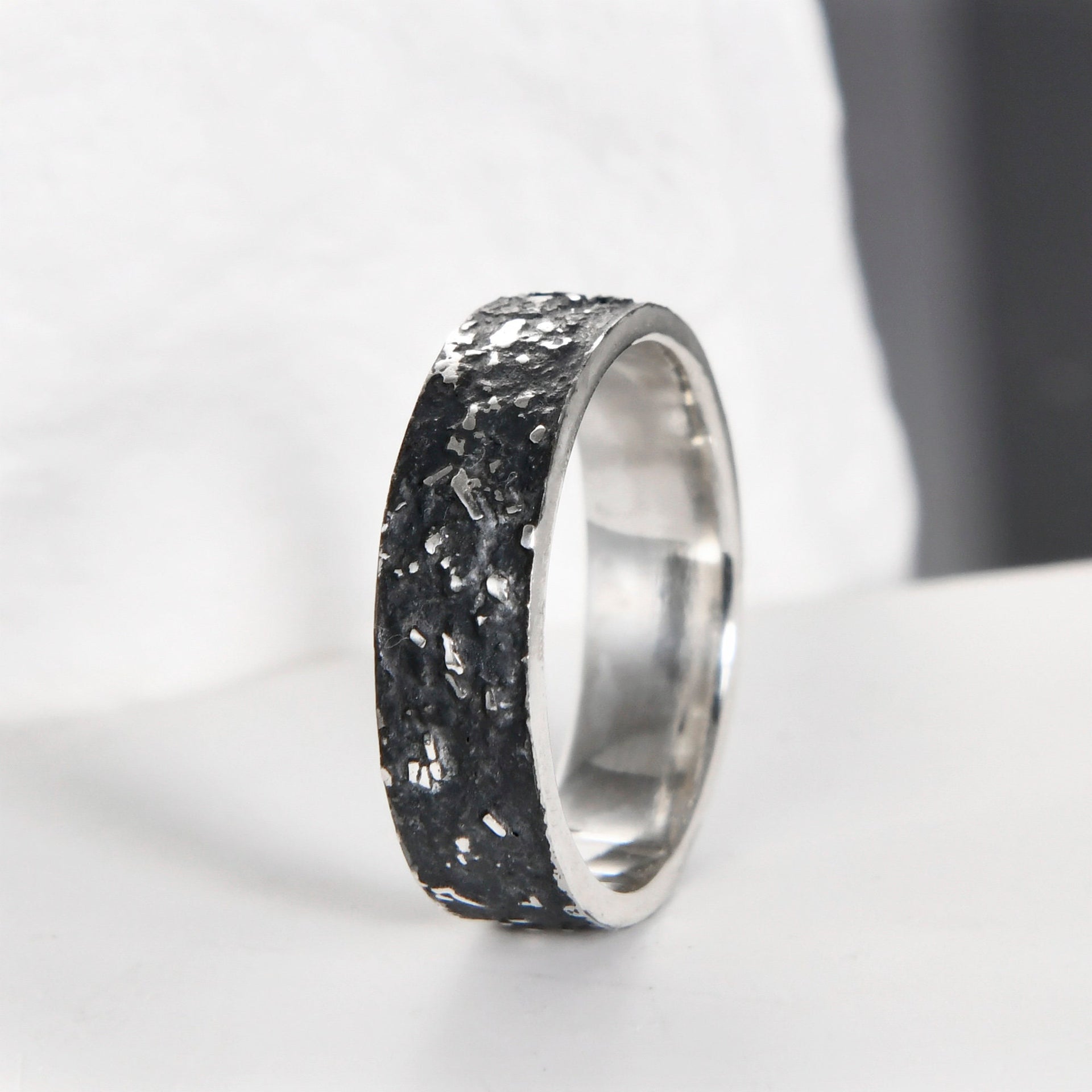 Close-up of the dark fused lava texture on a 6mm rustic sterling silver galaxy band.