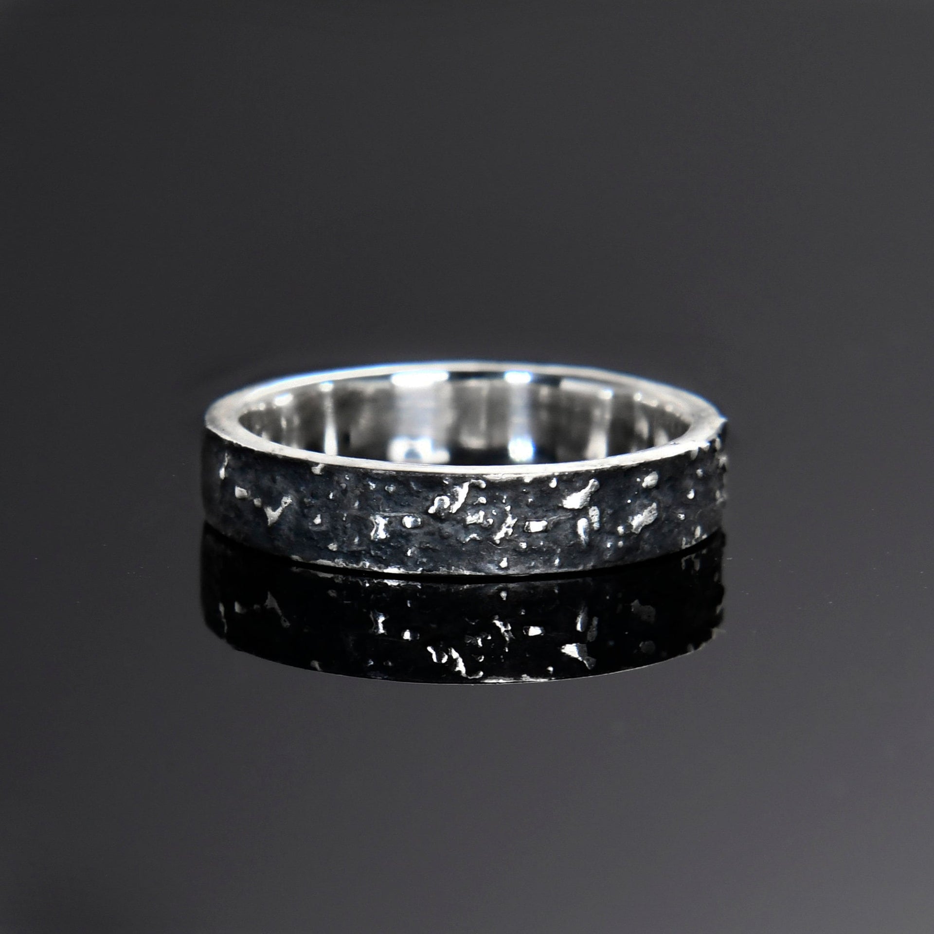 Side view of the 4mm galaxy ring showing its narrow profile, oxidized surface, and polished edges.