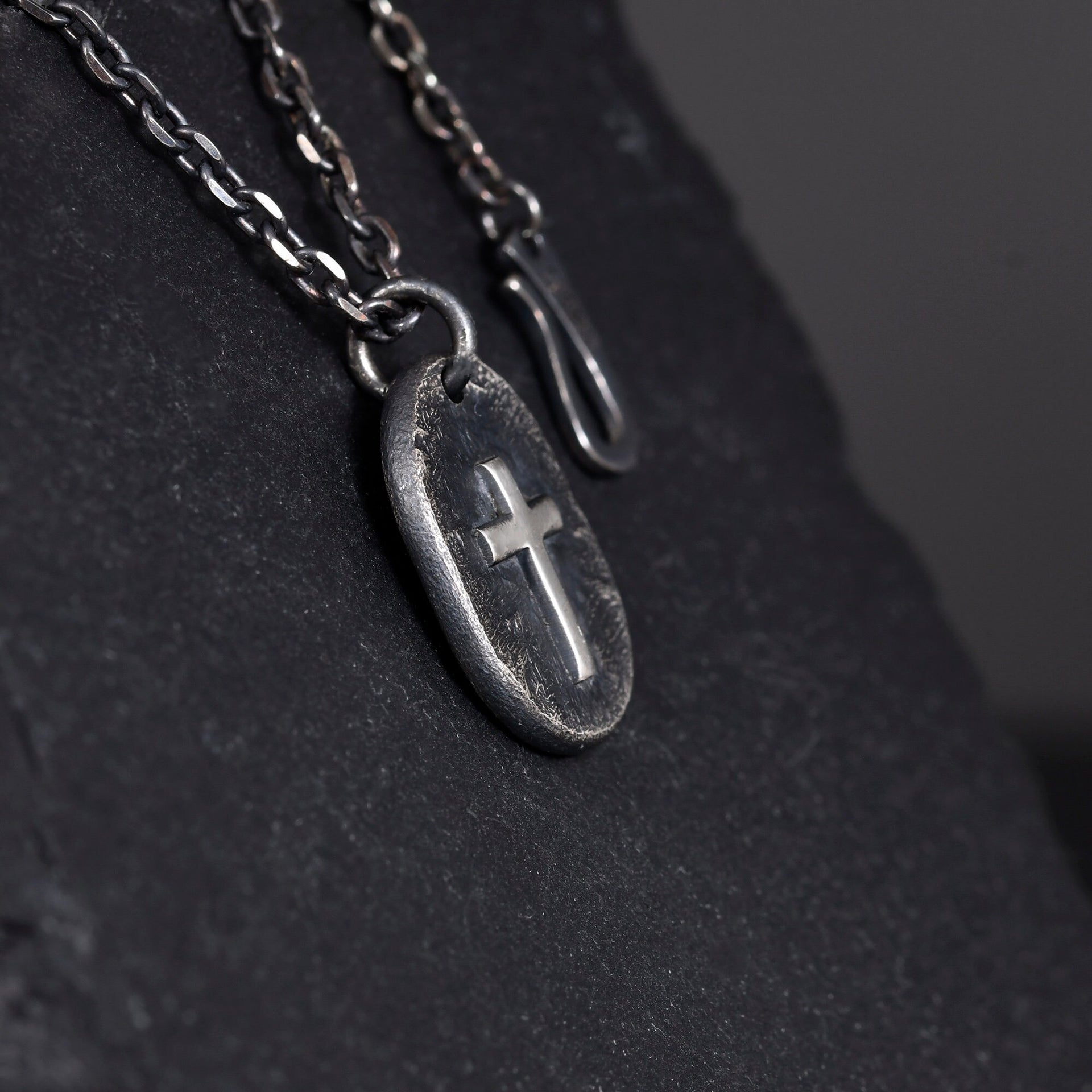 Oxidized sterling silver cross pendant shown close up with handmade texture