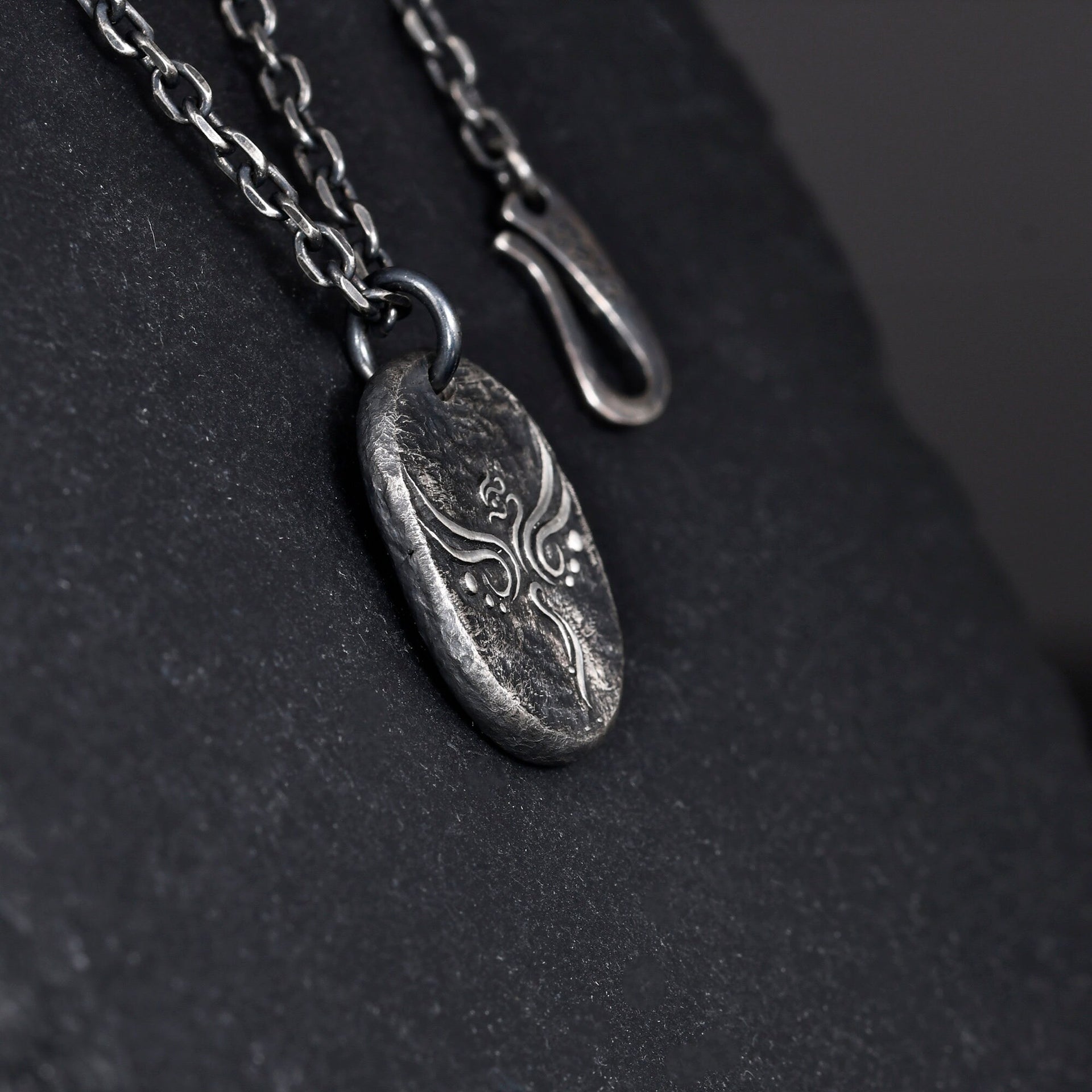 Oxidized sterling silver phoenix pendant shown close up with carved texture