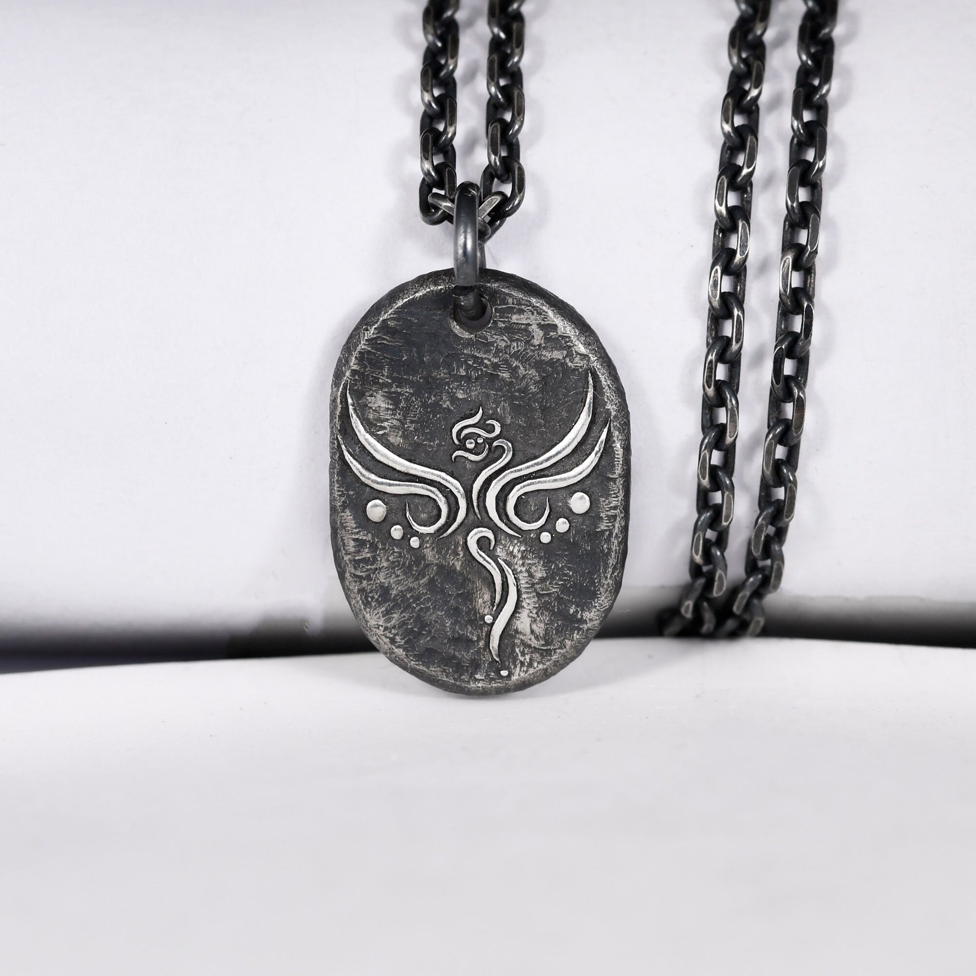 Rustic silver phoenix pendant worn as everyday symbolic jewelry