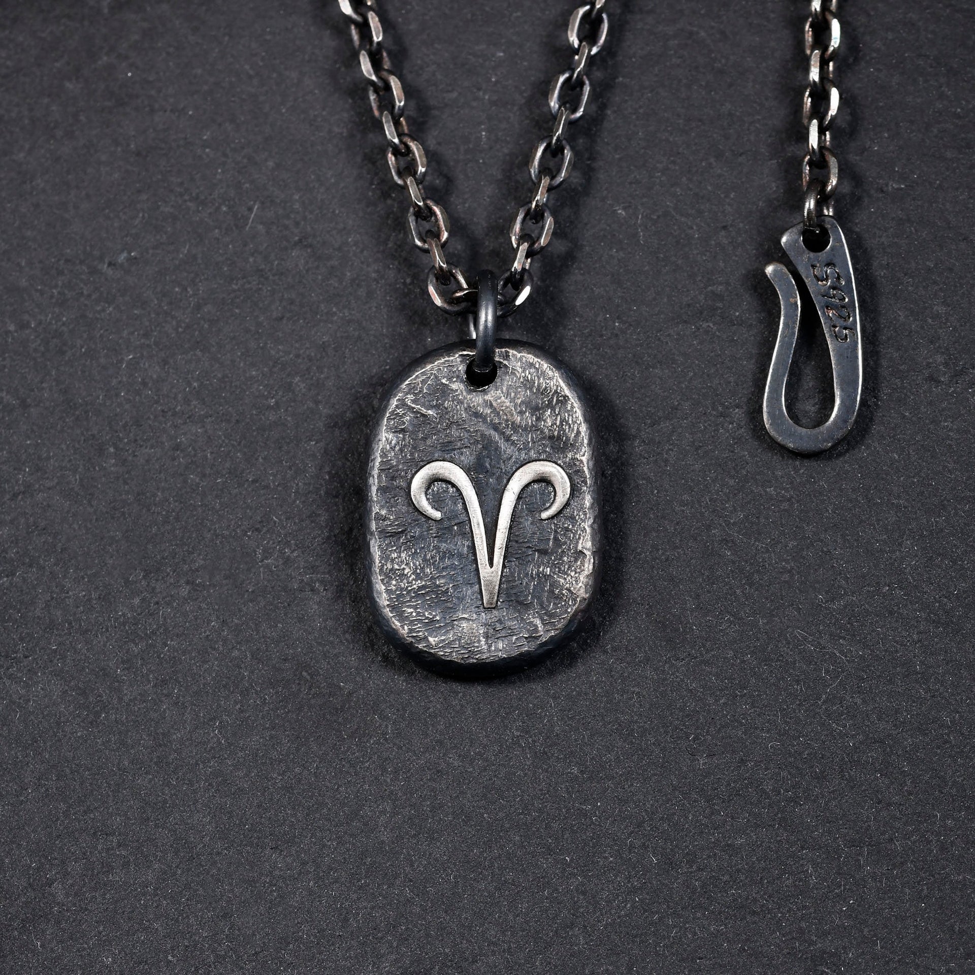 Sterling silver zodiac pendant shown close up with handmade finish