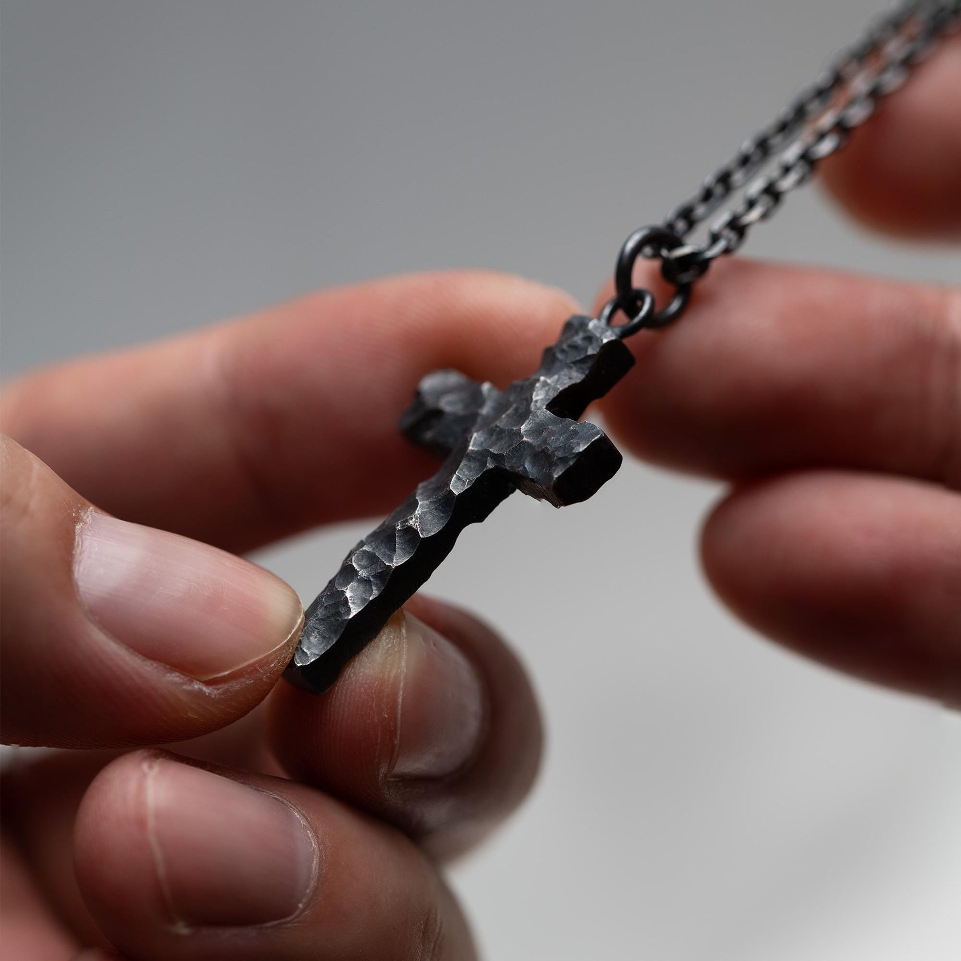 Rustic Christian cross pendant showing carved rock texture and silver edges