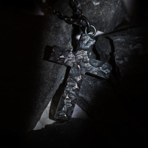 Sterling silver cross pendant with rugged black rock texture close up
