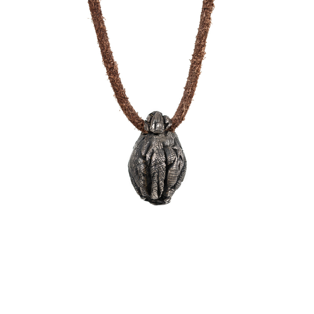 Back of the beanie skull pendant showing the ribbed knit texture of the hat and the leather cord loop, oxidized nickel silver