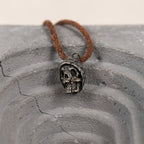Beanie skull pendant on a cracked grey concrete arch, hand carved nickel silver hatted skull necklace