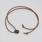 Full dark brown leather cord laid out in a loop with the beanie skull pendant, slider bead and knotted ends