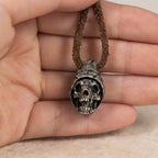 Beanie skull pendant held in an open palm on its leather cord, showing the pendant size in the hand
