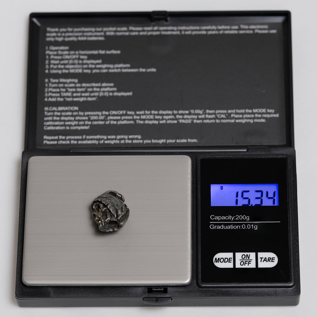 Beanie skull pendant on a digital pocket scale reading 15.34 g, oxidized nickel silver