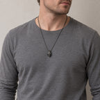 Man in a grey long-sleeve shirt wearing the beanie skull pendant on a dark chain at mid-chest