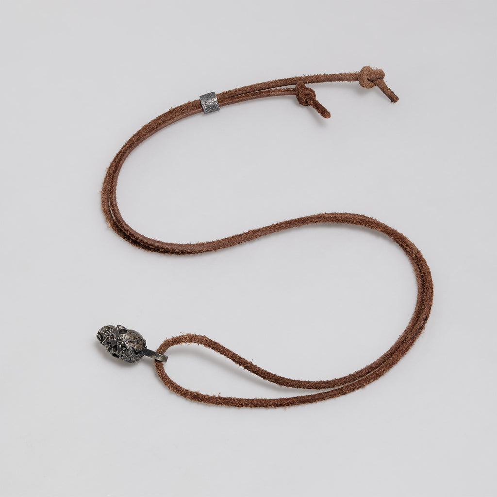 Full dark brown leather cord laid out in a loop with the exposed brain skull pendant, slider bead and knotted ends