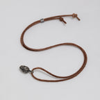 Full dark brown leather cord laid out in a loop with the exposed brain skull pendant, slider bead and knotted ends