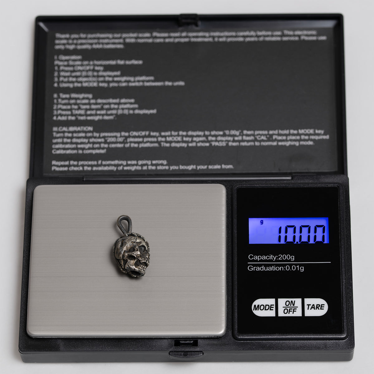 Exposed brain skull pendant on a digital pocket scale reading 10.00 g, oxidized nickel silver
