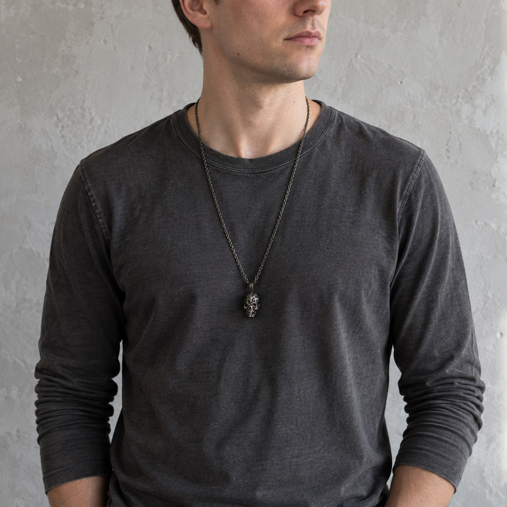 Young man in a dark shirt wearing the exposed brain skull pendant on a dark chain at mid-chest