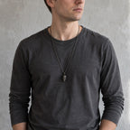 Young man in a dark shirt wearing the exposed brain skull pendant on a dark chain at mid-chest