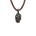 Men's exposed brain skull necklace in oxidized nickel silver, front view of the hand carved skull pendant with an open cranium on a dark brown leather cord, white background