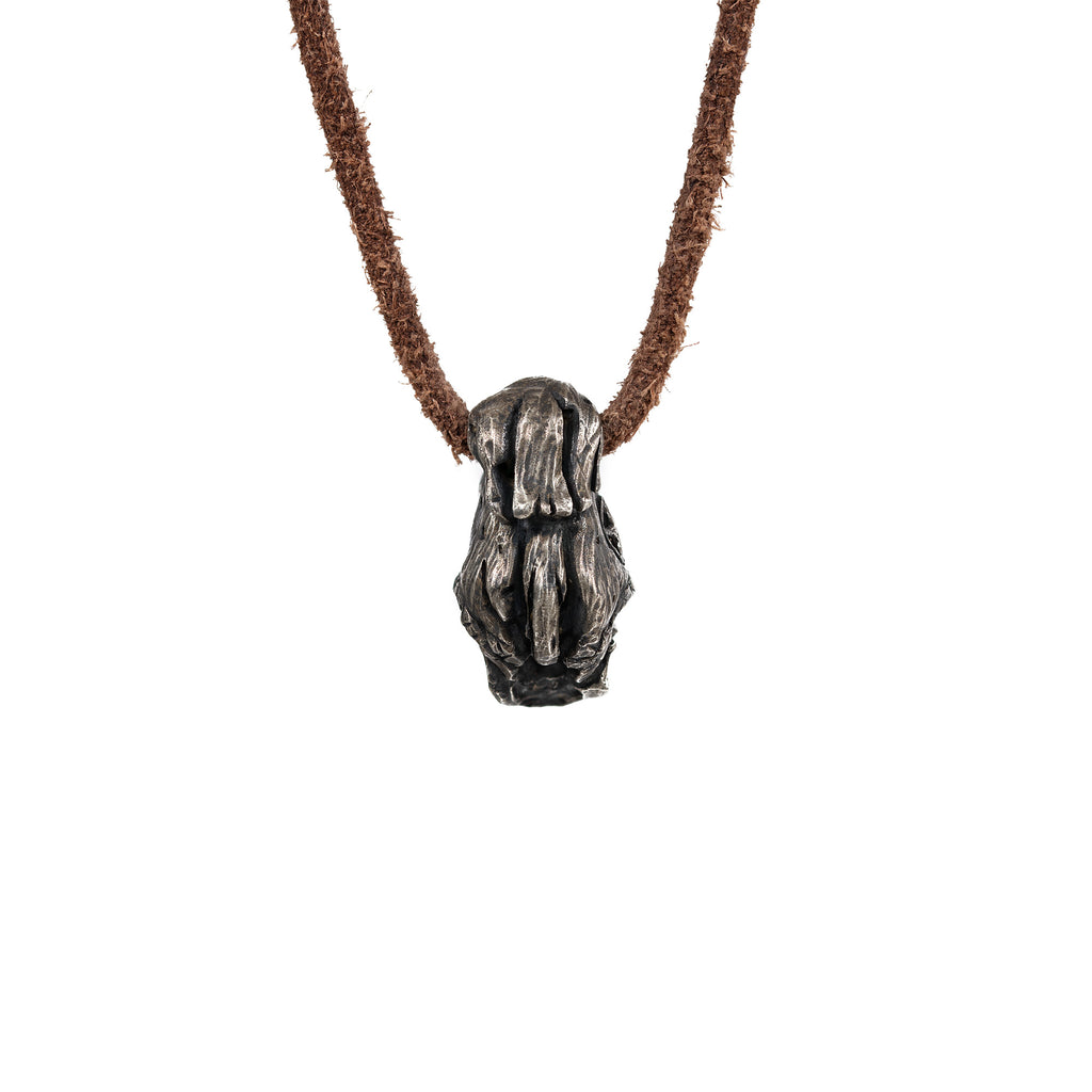 Back of the top hat skull pendant showing the cross-hatched carved hat and the leather cord loop, oxidized nickel silver