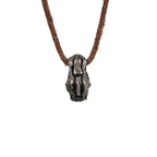 Back of the top hat skull pendant showing the cross-hatched carved hat and the leather cord loop, oxidized nickel silver