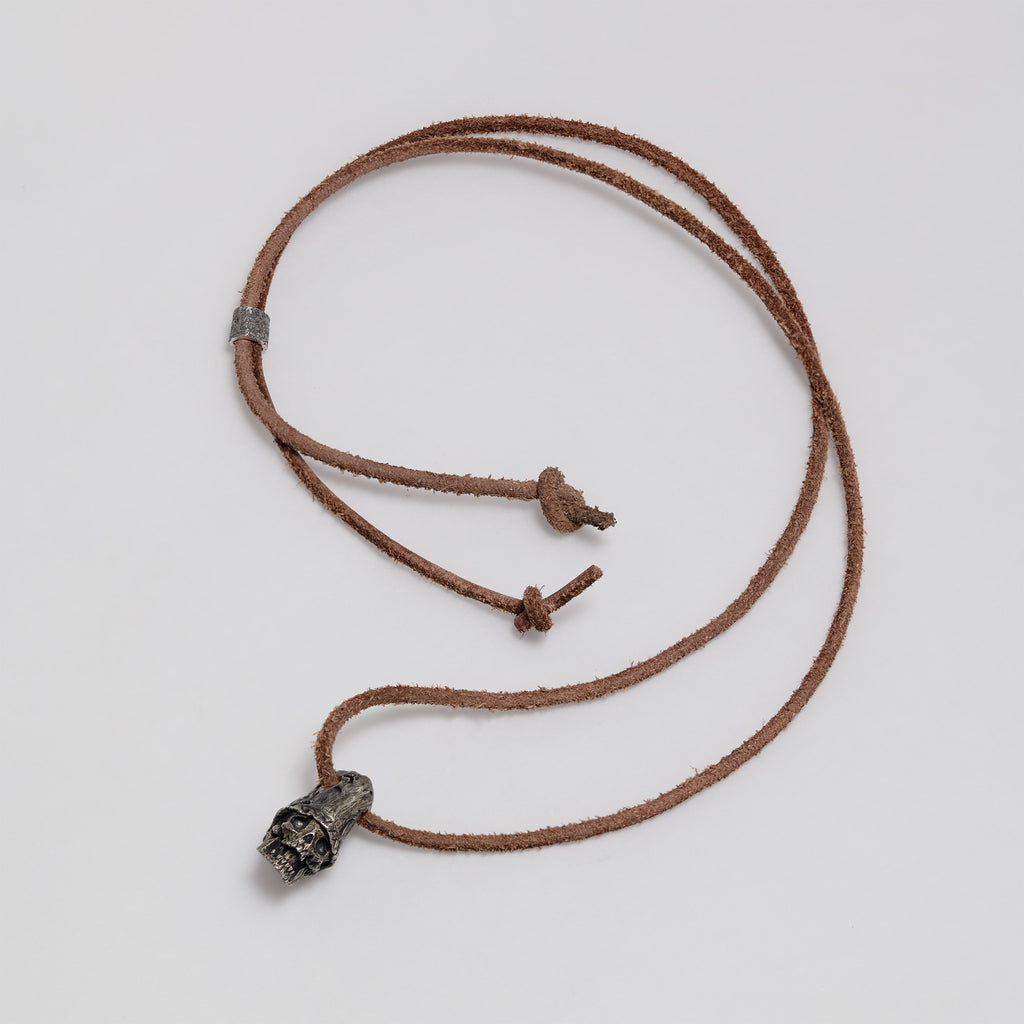 Full dark brown leather cord laid out in a loop with the top hat skull pendant, slider bead and knotted ends