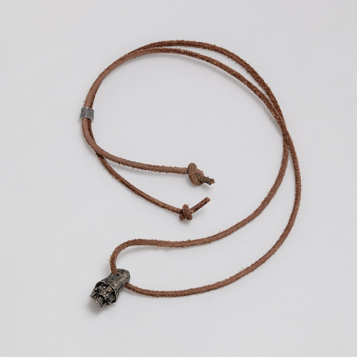 Full dark brown leather cord laid out in a loop with the top hat skull pendant, slider bead and knotted ends