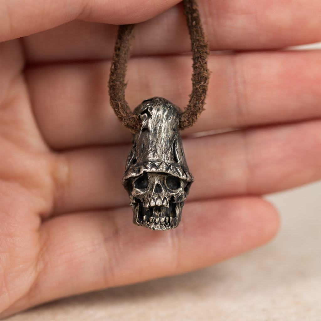 Top hat skull pendant held in an open palm on its leather cord, showing the pendant size in the hand