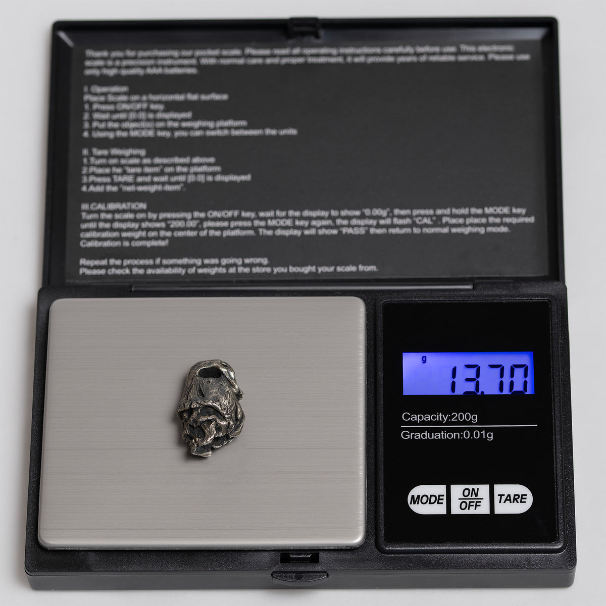 Top hat skull pendant on a digital pocket scale reading 13.70 g, oxidized nickel silver