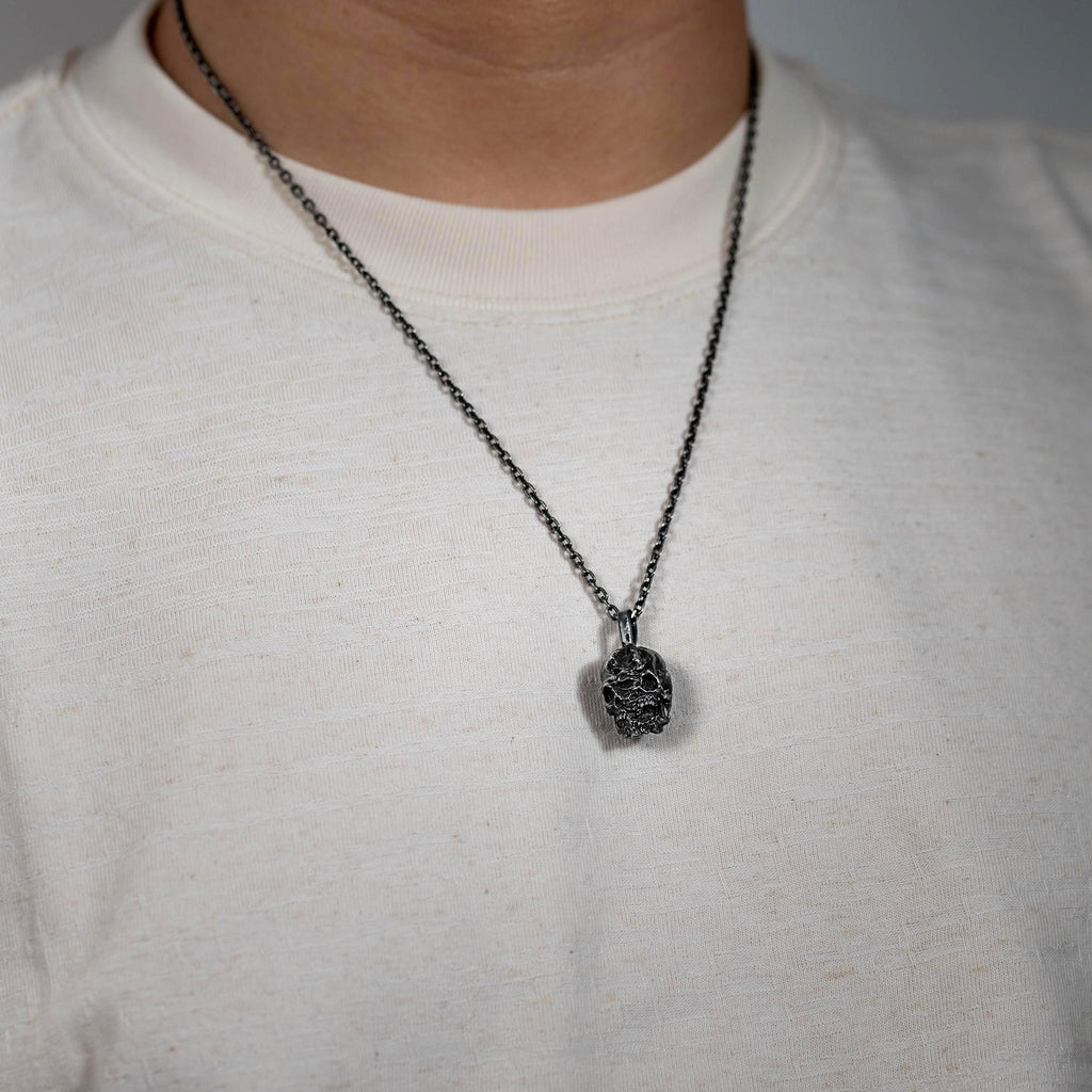 Model wearing the double-face skull pendant on a plain t-shirt for everyday styling.