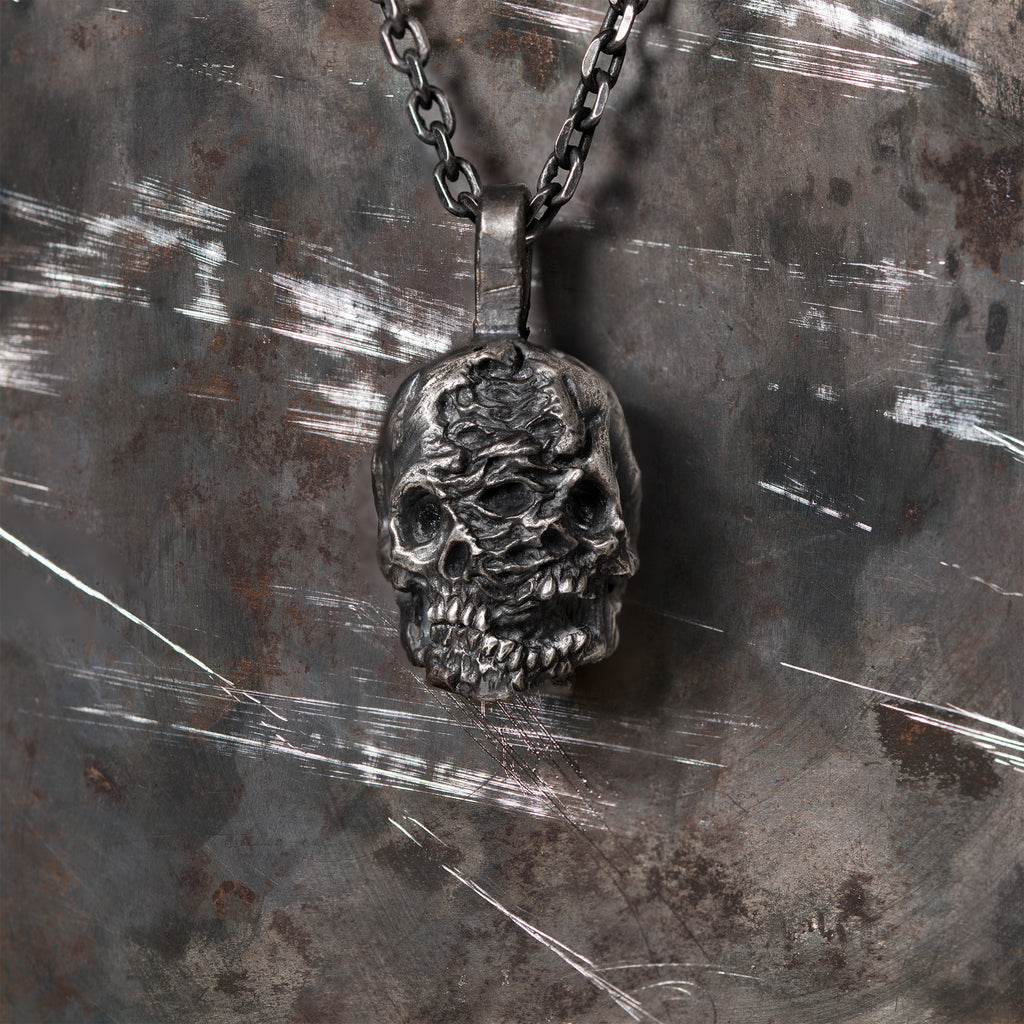 Double-face skull pendant in oxidized 925 sterling silver, lit to show its carved sculptural depth.
