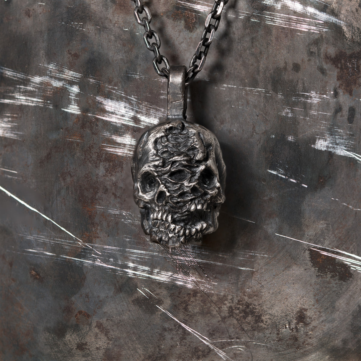 Double-face skull pendant in oxidized 925 sterling silver, lit to show its carved sculptural depth.