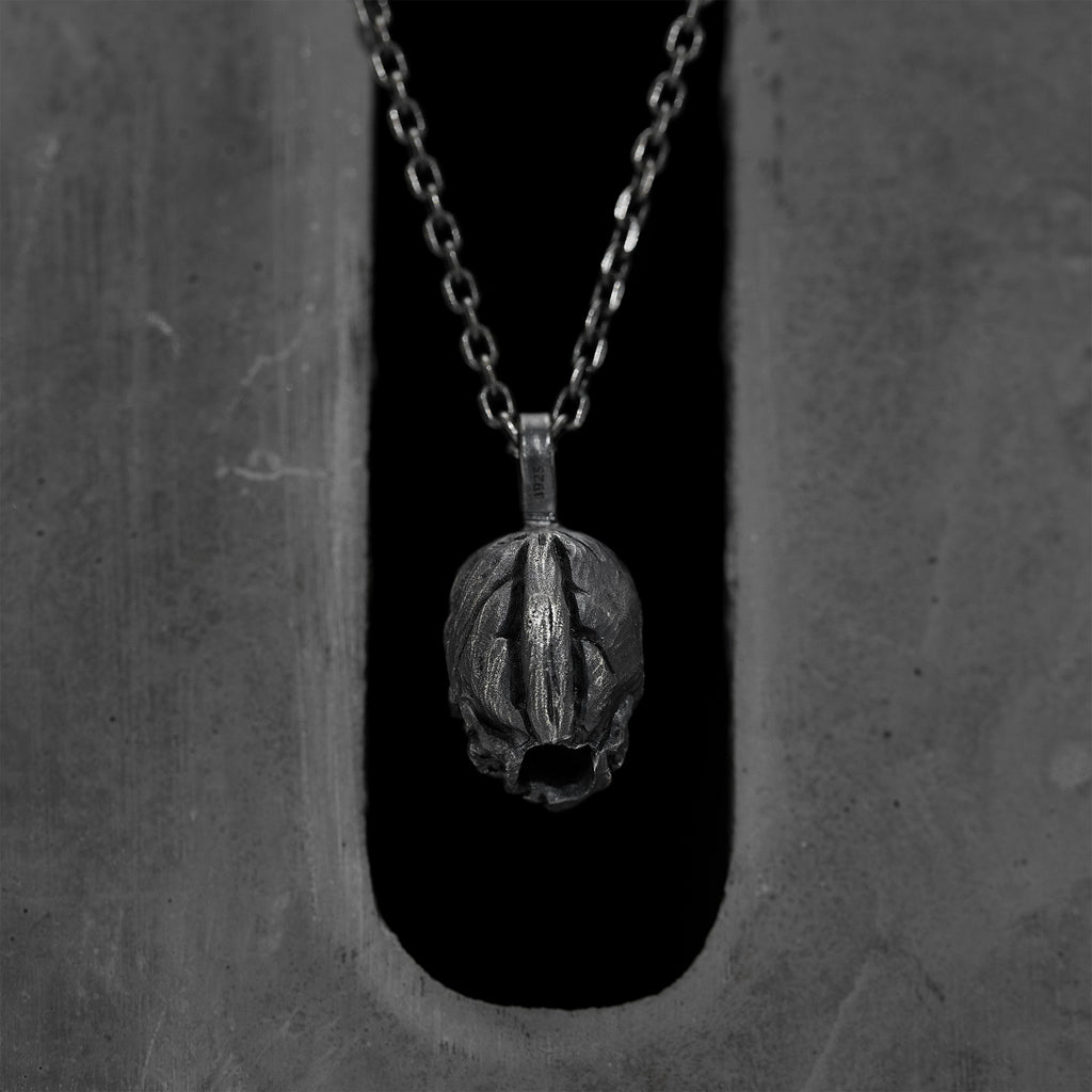 Back of the double faced skull pendant: a domed, striated silver surface with no face, 925 stamped on the bail.