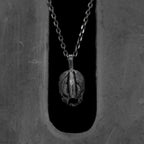Back of the double faced skull pendant: a domed, striated silver surface with no face, 925 stamped on the bail.