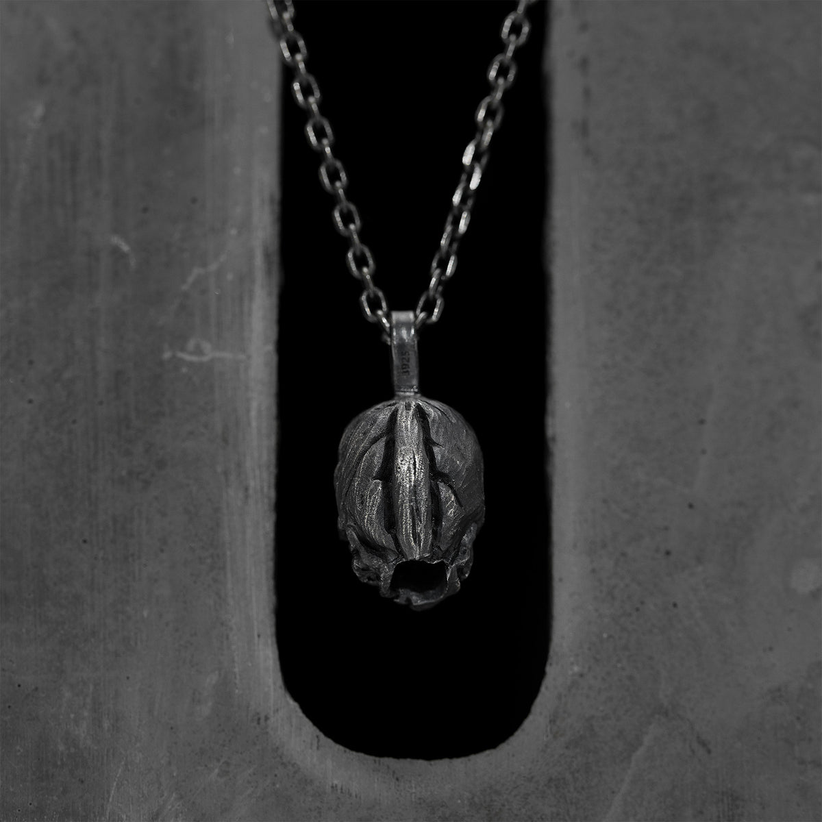 Back of the double faced skull pendant: a domed, striated silver surface with no face, 925 stamped on the bail.