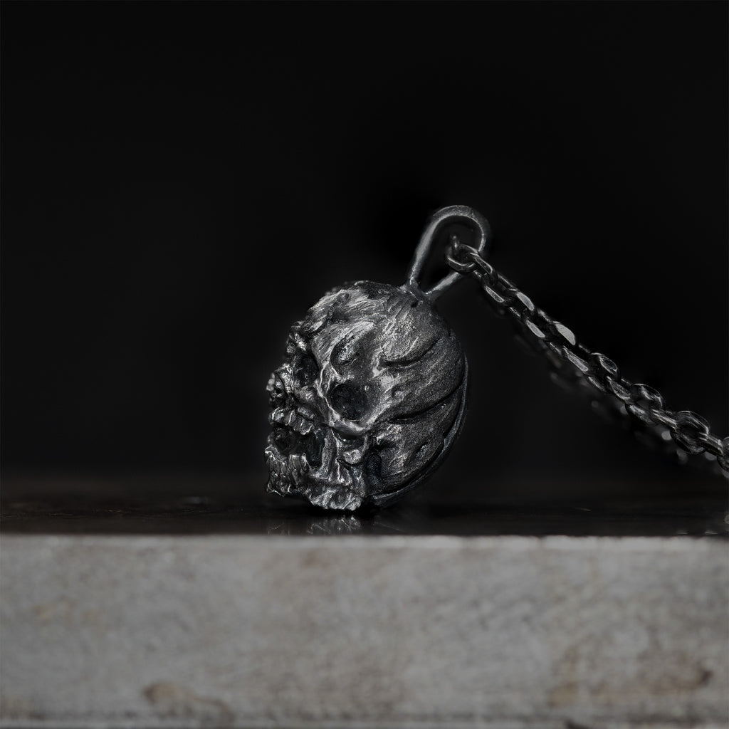 Side view of the oxidized skull pendant showing its depth and carved profile.