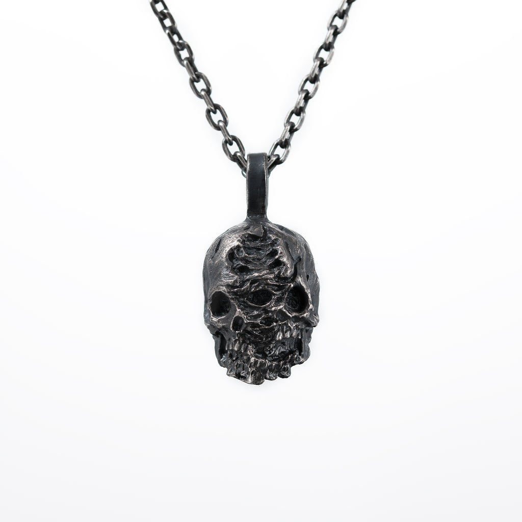 Front view of the double faced skull pendant in oxidized 925 sterling silver on a white background, hanging from a dark chain.
