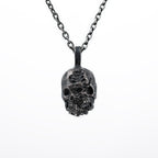Front view of the double faced skull pendant in oxidized 925 sterling silver on a white background, hanging from a dark chain.
