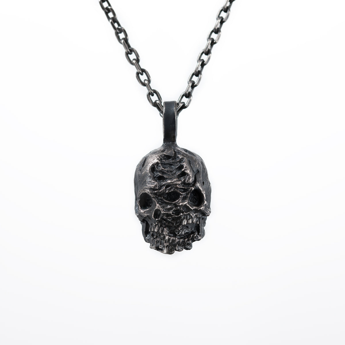Front view of the double faced skull pendant in oxidized 925 sterling silver on a white background, hanging from a dark chain.