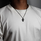 Black oxidized sterling silver rock texture pendant worn on a white T-shirt to show necklace scale and fit.